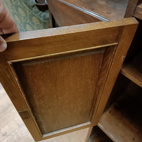 1049 - An Art Nouveau style oak bookcase, with a pierced top rail, above shelves and two cupboard doors, in... 