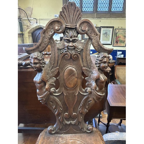 1045 - A pair of 19th century Italian carved hall chairs, decorated figural forms, masks and foliage (2)