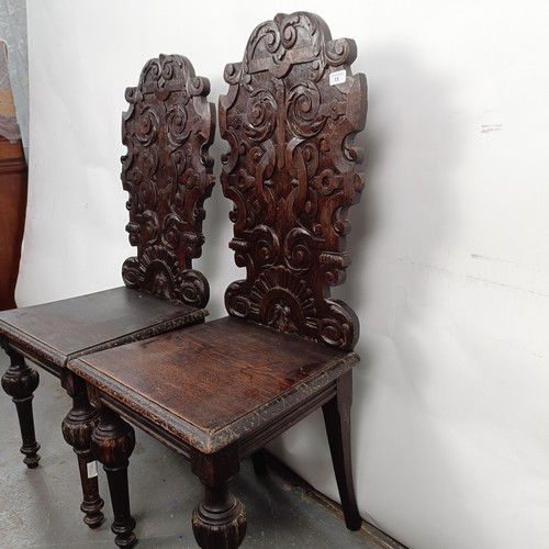 15 - A Victorian pair of oak hall chairs, with carved backs (2)