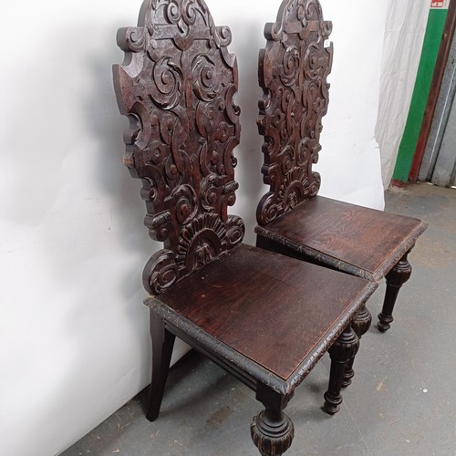 15 - A Victorian pair of oak hall chairs, with carved backs (2)