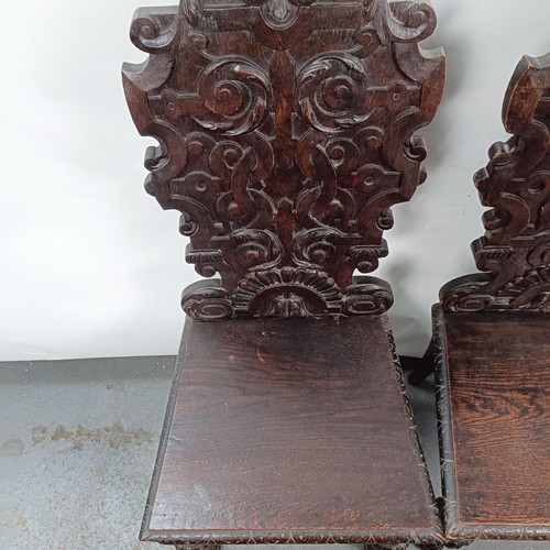 15 - A Victorian pair of oak hall chairs, with carved backs (2)