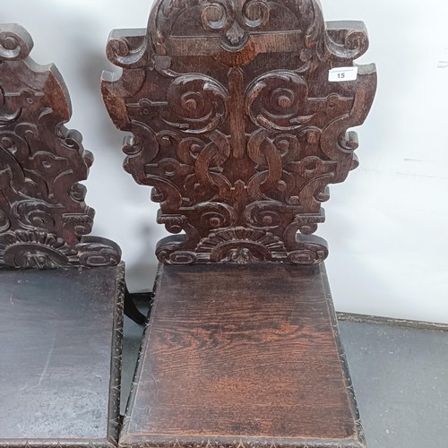 15 - A Victorian pair of oak hall chairs, with carved backs (2)