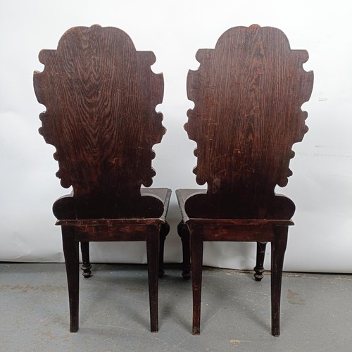 15 - A Victorian pair of oak hall chairs, with carved backs (2)