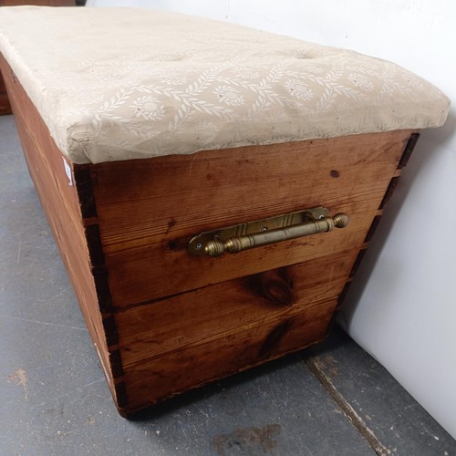 25 - A pine ottoman, with an upholstered top and brass handles, 124 cm wide