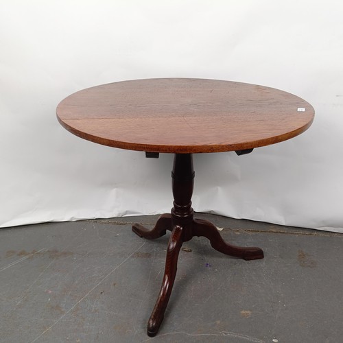 101 - An oak wine table, on a column support to a tripod base, 82 cm diameter