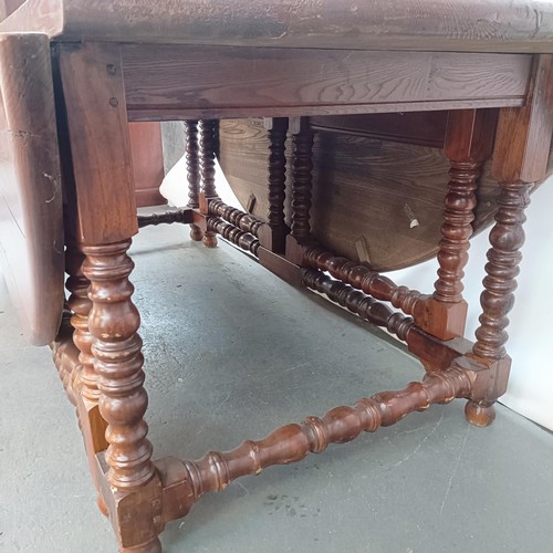 115 - An 18th century style oak gateleg dining table, on bobbin turned legs, 203 cm wide