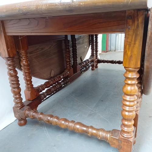 115 - An 18th century style oak gateleg dining table, on bobbin turned legs, 203 cm wide