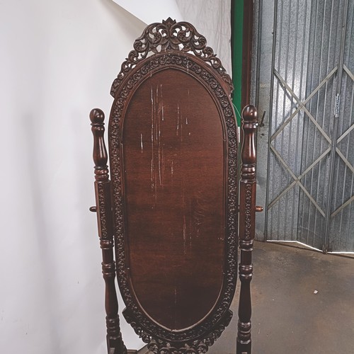 250 - A hardwood cheval mirror, profusely carved with foliate forms, 184 x 70 cm