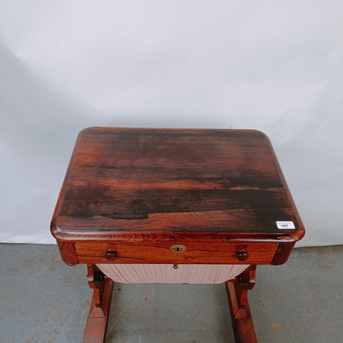 167 - A 19th century rosewood work table, with a single drawer above a silk rag box, on twin end supports ... 