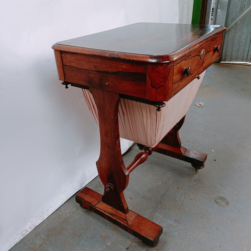 167 - A 19th century rosewood work table, with a single drawer above a silk rag box, on twin end supports ... 