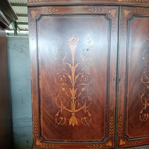 6 - A late 19th century Sheraton Revival inlaid mahogany bow front linen press, two cupboard doors to re...