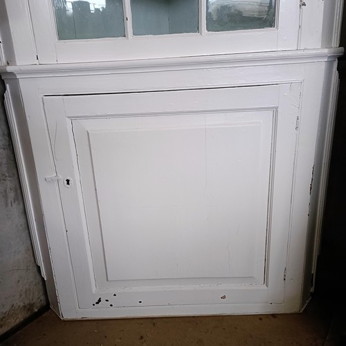 11 - A painted corner cupboard, the top with a glazed door, on a base with a cupboard door, 105 cm widePl... 