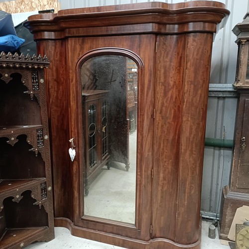 140 - A Victorian mahogany serpentine wardrobe, with a mirrored door, the interior with drawers and slides... 