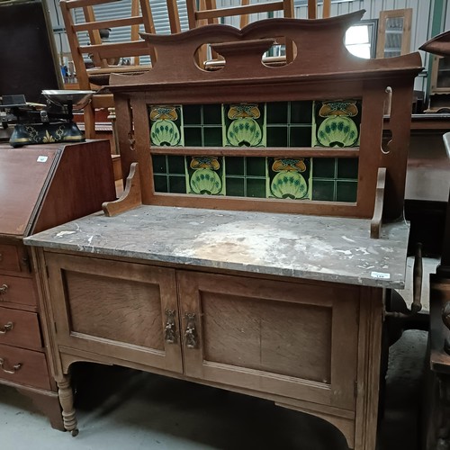 148 - An early 20th century washstand, with a tiled back, marble top with two cupboard doors, 110 cm wideP... 