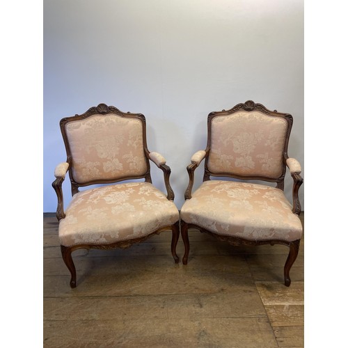 1346 - A pair of late 19th/early 20th century walnut framed armchairs, with a carved top rail, padded back ... 