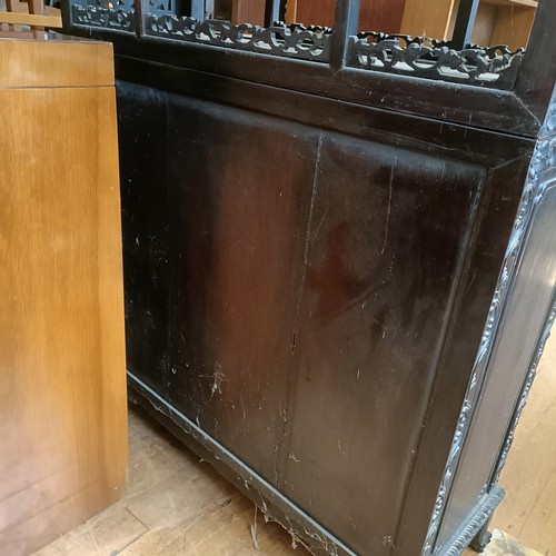 876 - A Chinese hardwood cabinet, the top with stepped shelves, on a base with two cupboard doors, profuse... 