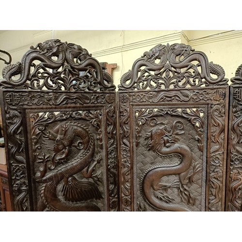 878 - A Chinese carved four fold screen, decorated dragons and flowers, each panel 190 cm high x 50 cm wid... 