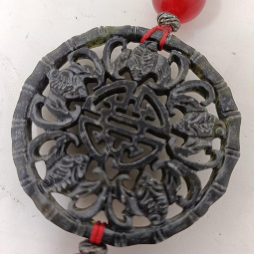 911 - A Chinese hardstone carved plaque, 8 cm diameter, with attached tassel, another, 5 cm diameter (2)