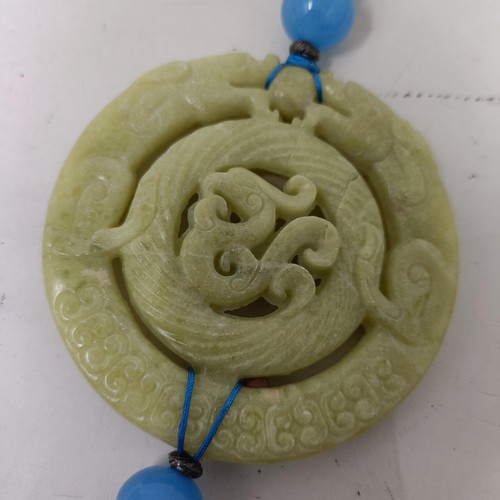 911 - A Chinese hardstone carved plaque, 8 cm diameter, with attached tassel, another, 5 cm diameter (2)