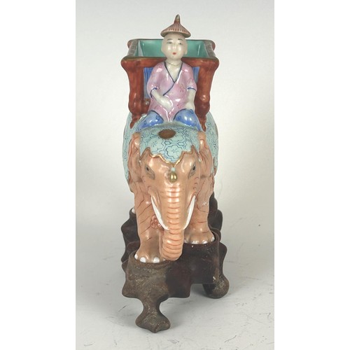 835 - A porcelain figure of an elephant with a rider, on a carved wooden base, 14.5 cm high