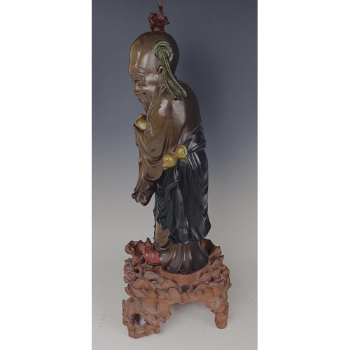 945 - A Chinese carved and painted figure, of a sage, on a pierced base, 48 cm high