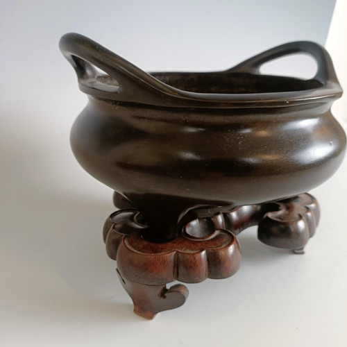 801 - A Chinese bronze tripod censer, character mark to base, 23 cm diameter, on a carved hardwood base (2... 