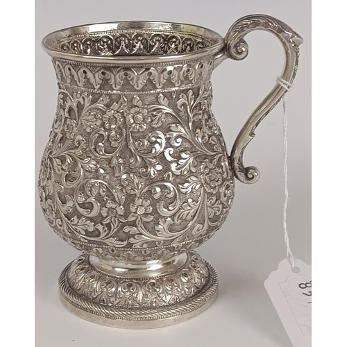 130 - A 19th century Indian silver coloured metal mug, embossed flowers and foliage, 12.5 cm high