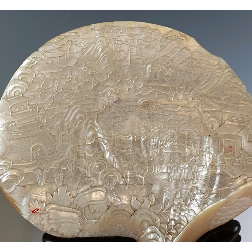 932 - A large pair of Chinese mother of pearl bi-discs, carved figures, horses, dwellings and fish, on car... 