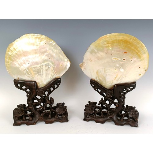 932 - A large pair of Chinese mother of pearl bi-discs, carved figures, horses, dwellings and fish, on car... 