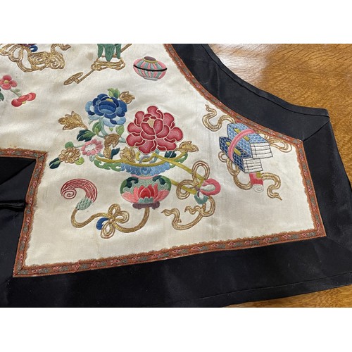 890 - A Chinese silk embroidered sleeveless jacket, decorated vases, flowers and other motifs