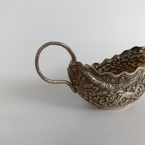 150 - A silver coloured metal sauce boat, with emobossed decoration