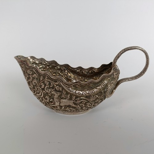 150 - A silver coloured metal sauce boat, with emobossed decoration