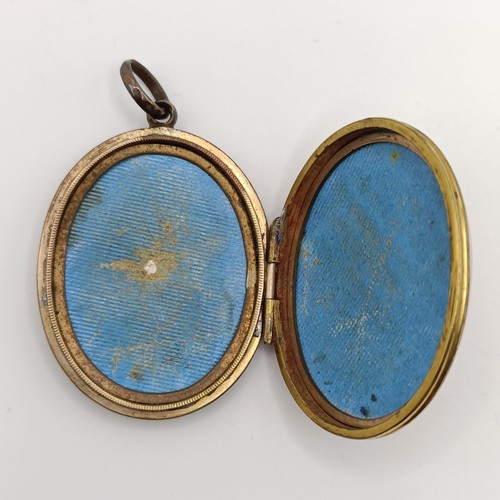 337 - An early 20th century silver gilt and enamel oval locket