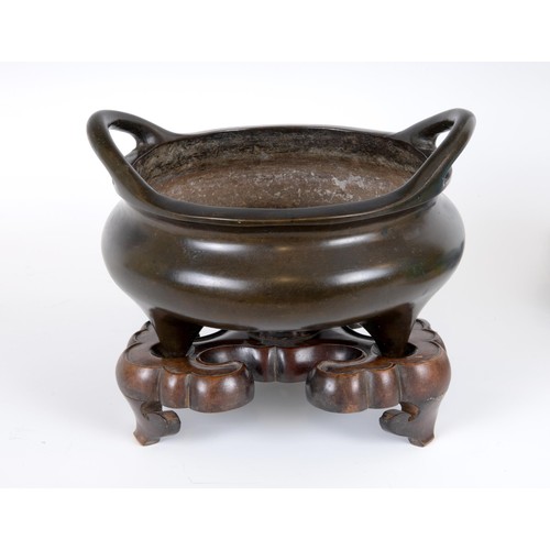 801 - A Chinese bronze tripod censer, character mark to base, 23 cm diameter, on a carved hardwood base (2... 