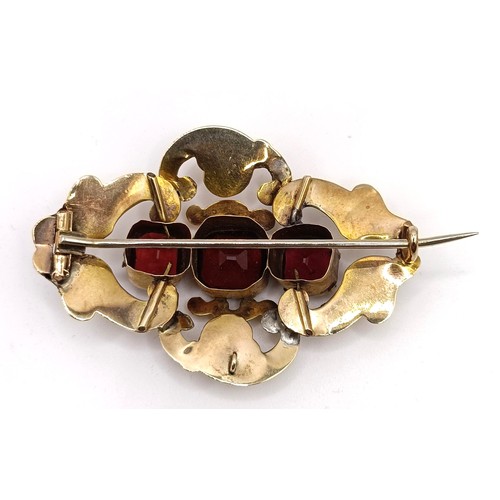 488 - A late 19th century yellow coloured metal and red stone brooch, in a vintage jewellery box