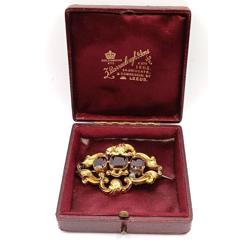 488 - A late 19th century yellow coloured metal and red stone brooch, in a vintage jewellery box