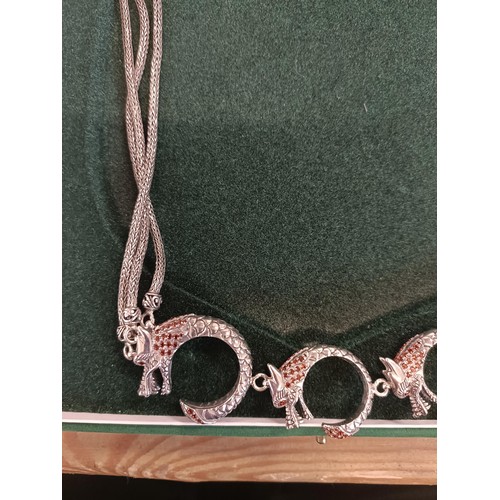 546 - A silver coloured metal and red stone necklace, in the form of four dragons, cased