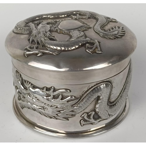 1011 - A Chinese silver coloured metal box, decorated a  dragon, 10 cm diameter...