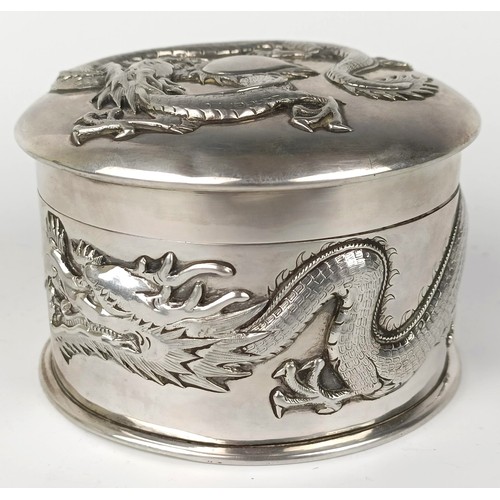 1011 - A Chinese silver coloured metal box, decorated a  dragon, 10 cm diameter