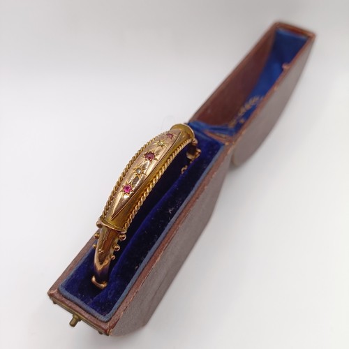 482 - An early 20th century yellow coloured metal, red and white stone bangle, in a vintage jewellery box