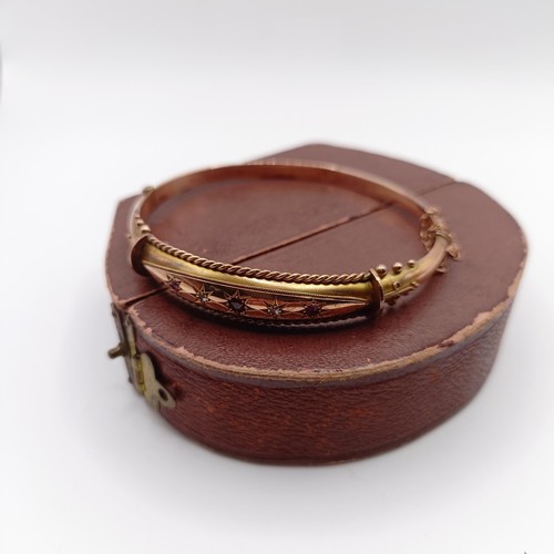 482 - An early 20th century yellow coloured metal, red and white stone bangle, in a vintage jewellery box