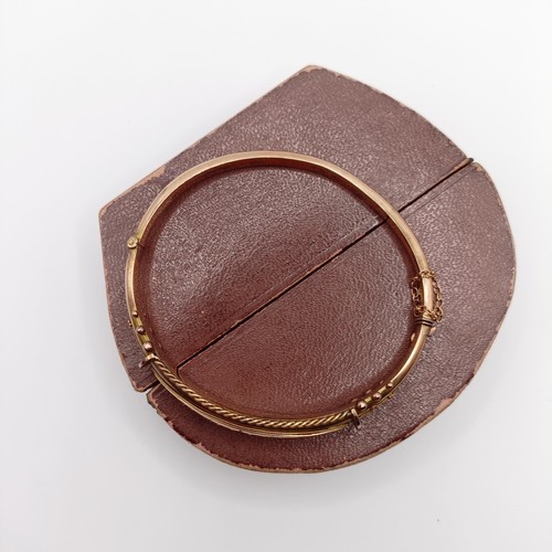 482 - An early 20th century yellow coloured metal, red and white stone bangle, in a vintage jewellery box