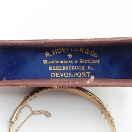 482 - An early 20th century yellow coloured metal, red and white stone bangle, in a vintage jewellery box