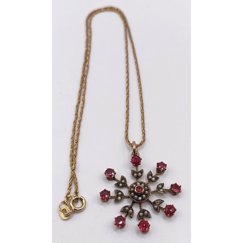 628 - A yellow metal, red stone and seed pearl floral brooch, on a chain