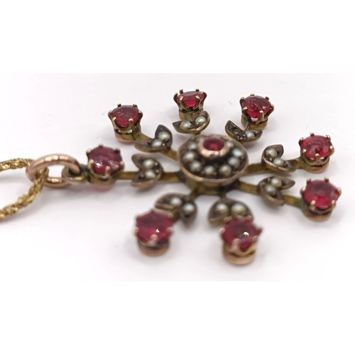 628 - A yellow metal, red stone and seed pearl floral brooch, on a chain