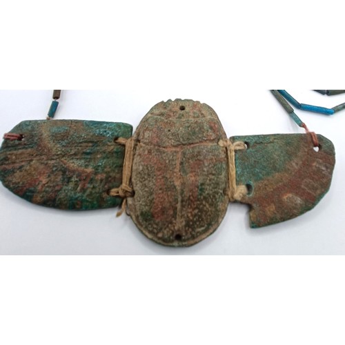 572 - An Egyptian turquoise faience winged scarab pendant, on a turquoise necklace, 12 cm wide