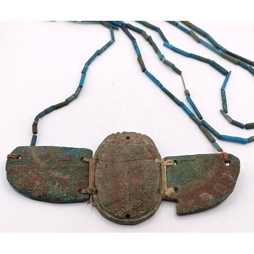 572 - An Egyptian turquoise faience winged scarab pendant, on a turquoise necklace, 12 cm wide