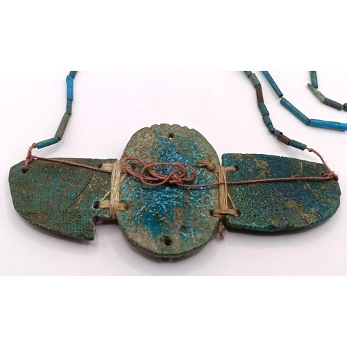 572 - An Egyptian turquoise faience winged scarab pendant, on a turquoise necklace, 12 cm wide