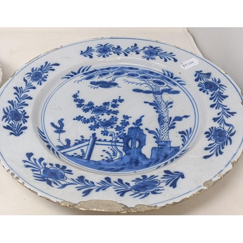 1101 - A blue and white Delft plate, decorated birds and flowers, 35 cm diameter, and another, decorated in...