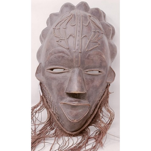 1121 - An African pottery mask, 24 cm high, and an African carved wooden mask, 32 cm (2)